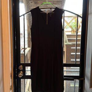 Black v neck with defined waistline, exposed back zipper.